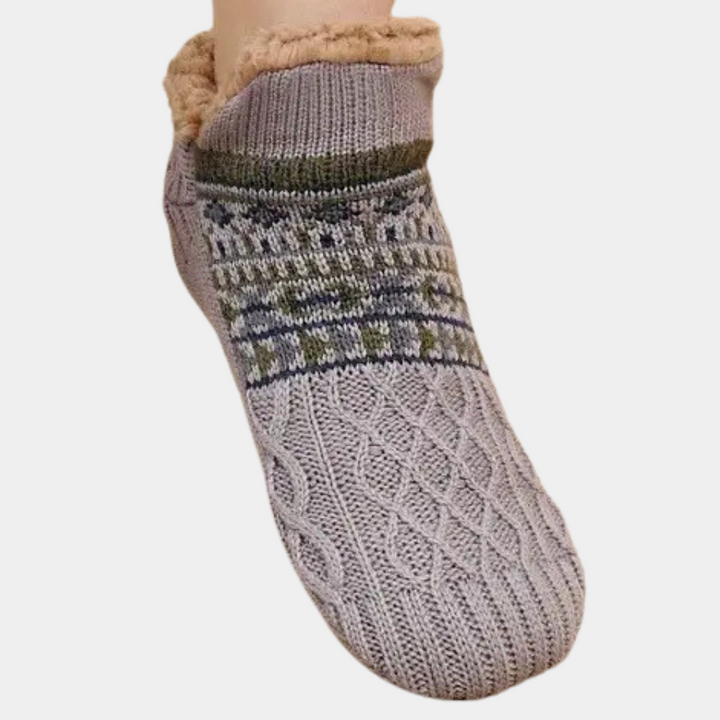 Grijze gebreide sok met Noors patroon en warme voering, ideaal voor wintercomfort. Perfecte keuze voor koude dagen en gezellige avonden thuis.