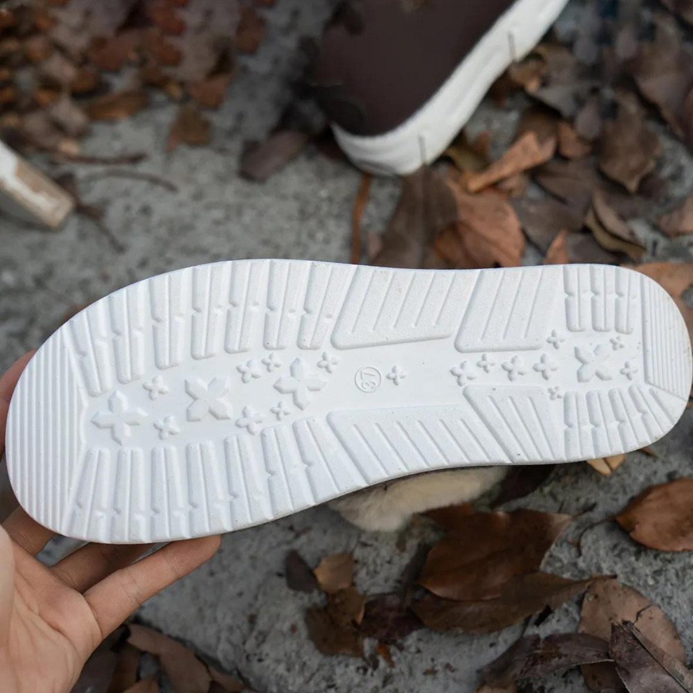 Witte rubberen schoenzool met antislipprofiel en stervormige patronen, vastgehouden boven herfstbladeren. Geschikt voor sneakers en casual schoenen.