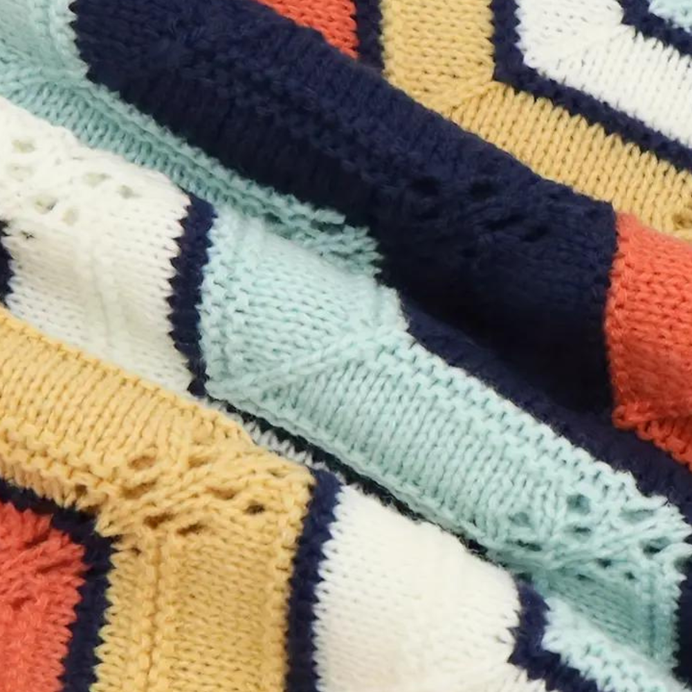 Gebreide deken met kleurrijke strepen in blauw, geel, wit en oranje. Zachte textuur, perfect voor interieurdecoratie en comfort.