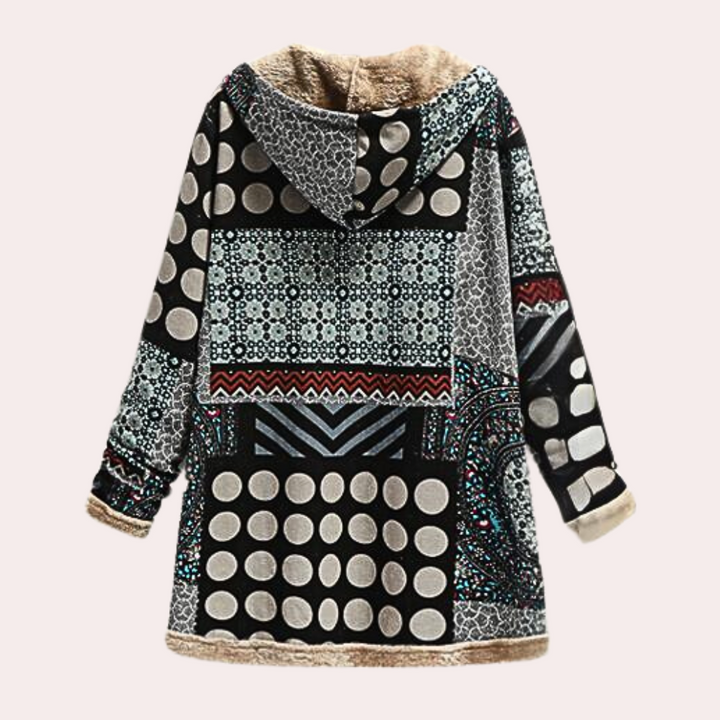Dames winterjas met capuchon, geometrisch patroon, zwart-wit stippen, etnisch design, warme voering, modieuze lange jas, trendy winterkleding.