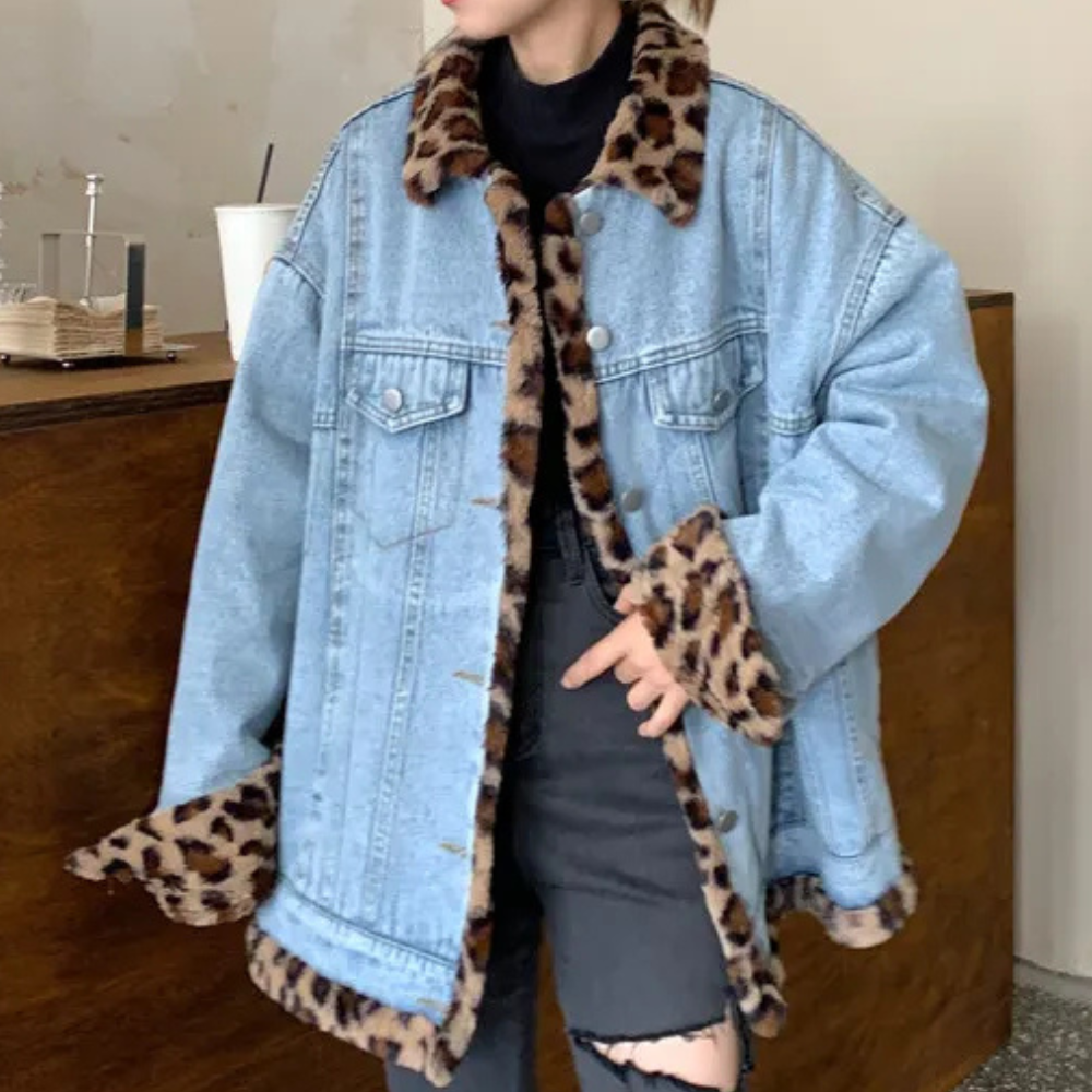 Vrouw draagt oversized spijkerjas met luipaardprint voering, zwarte coltrui en gescheurde zwarte jeans. Trendy herfstmode, casual streetwear.