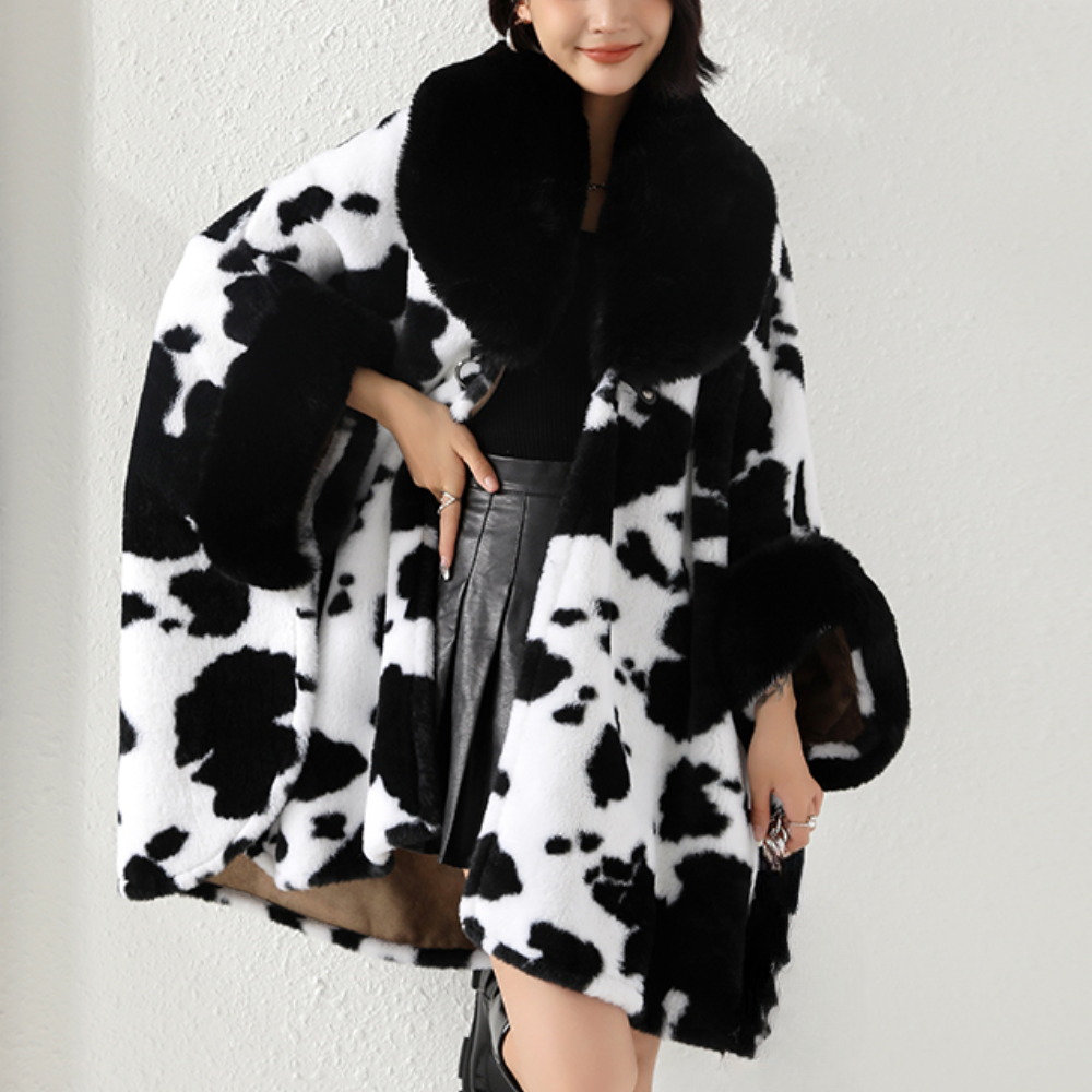 Vrouw in zwart-witte koeienprint bontjas, modieuze winterkleding, trendy damesmode, luxe uitstraling, stijlvolle outfit voor koude seizoenen.