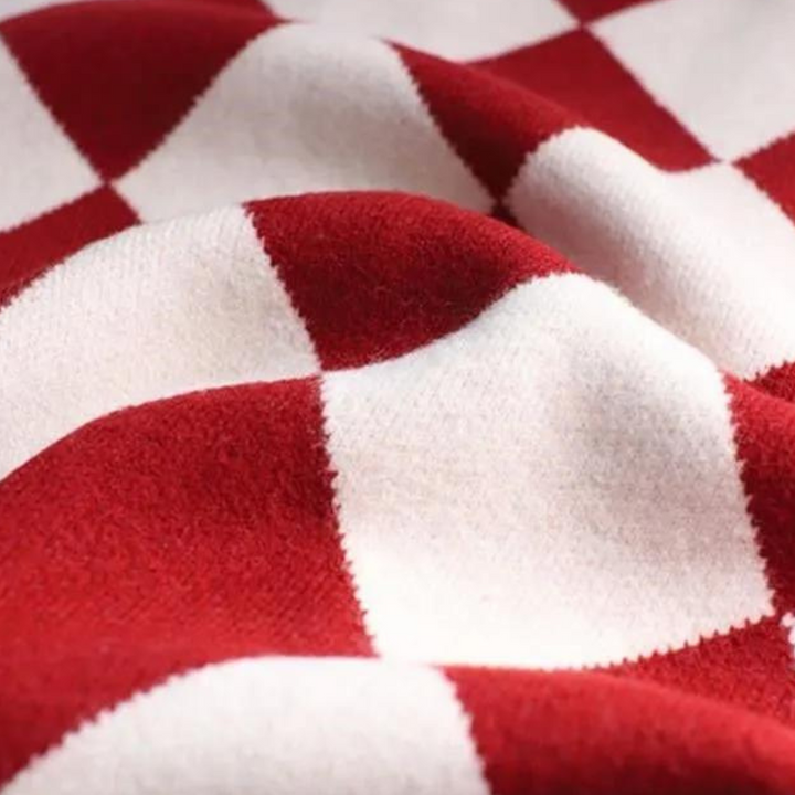 Rood-wit geruite wollen deken, close-up textuur. Zachte, warme plaid voor interieurdecoratie, perfect voor gezellige winteravonden.