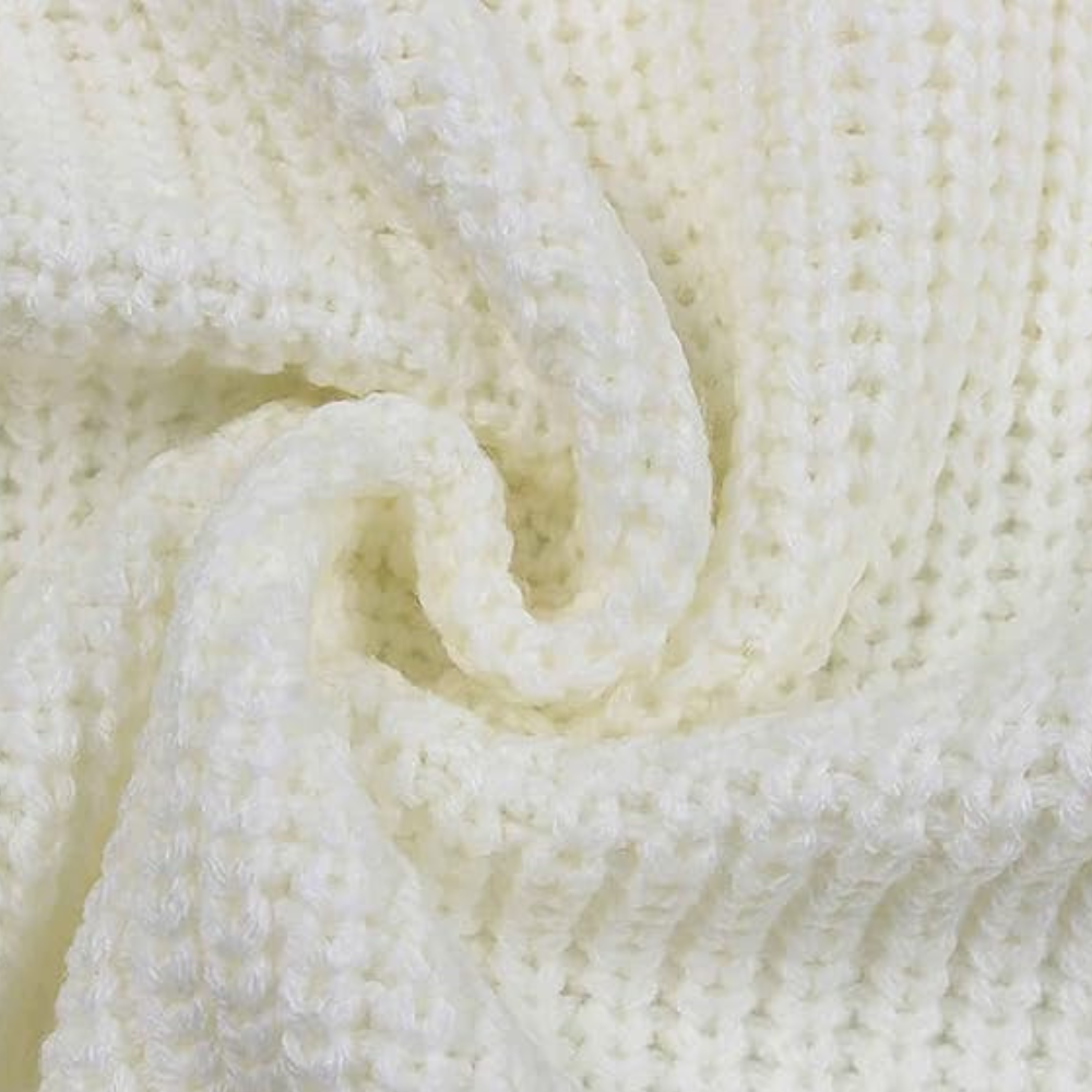 Witte gebreide deken close-up, zachte textuur, perfect voor interieurdecoratie, warme en comfortabele woonaccessoires, huiselijke sfeer.