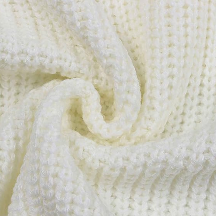 Witte gebreide deken close-up, zachte textuur, perfect voor interieurdecoratie, warme en comfortabele woonaccessoires, huiselijke sfeer.