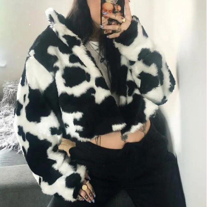 Vrouw in zwart-witte koeienprint jas, trendy wintermode, selfie in spiegel, casual outfit, populaire streetwear stijl, modeaccessoires.