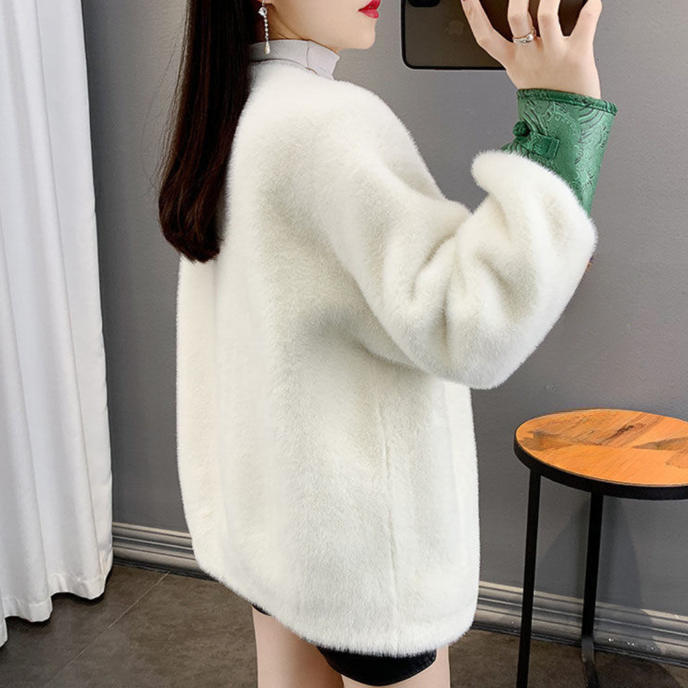 Vrouw in witte faux fur jas, groene blouse, zwarte rok, staand in moderne kamer. Stijlvolle wintermode, elegant design, trendy dameskleding.