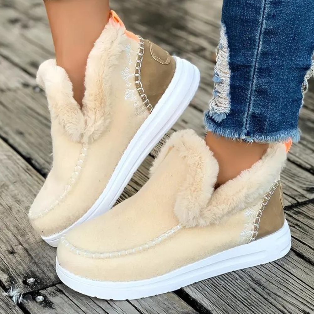 Beige winterlaarzen met bontvoering, witte zool en stiksels, gedragen op houten vloer. Modieuze dameslaarzen, warme schoenen, casual stijl.