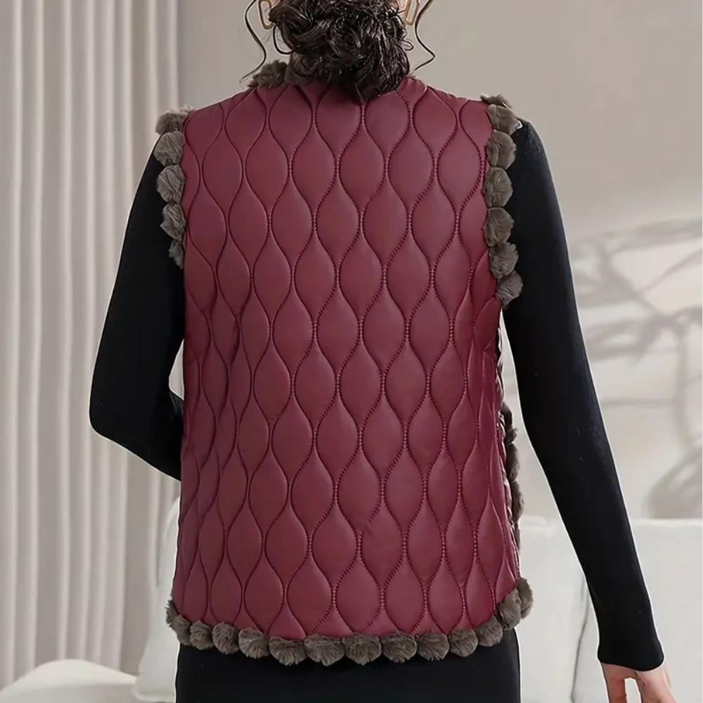 Vrouw draagt bordeauxrode gewatteerde bodywarmer met pompons, zwarte mouwen. Stijlvolle wintermode, warme dameskleding, trendy vest.