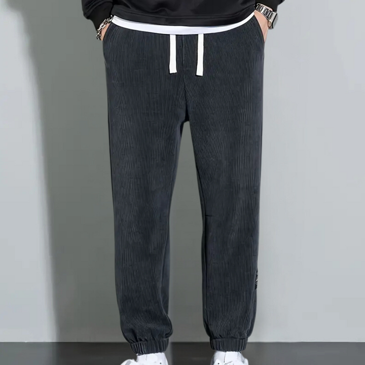 Donkergrijze corduroy joggingbroek voor heren met witte trekkoorden, casual sportieve stijl, ideaal voor dagelijks gebruik en comfortabele pasvorm.