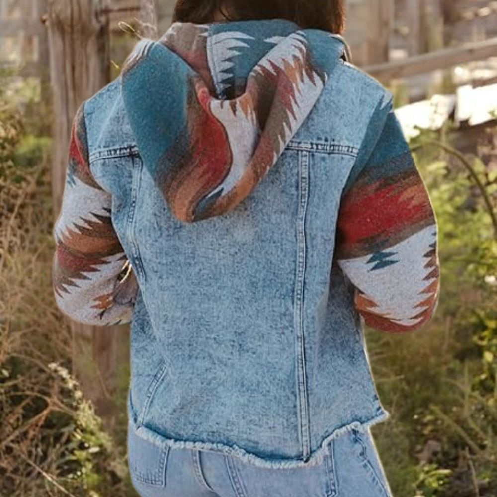 Vrouw in spijkerjack met kleurrijke, etnische print op mouwen en capuchon, buiten in natuurlijke omgeving. Modieuze dameskleding, herfststijl.