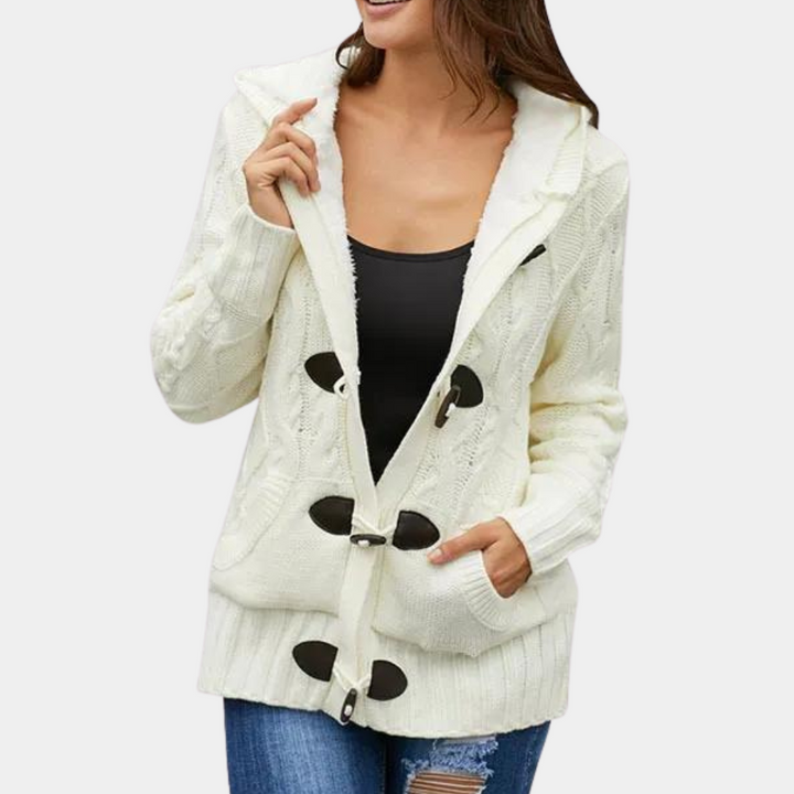 Vrouw draagt witte gebreide cardigan met houtje-touwtje sluiting, zwarte top en blauwe jeans. Stijlvolle damesmode, herfstkleding, casual outfit.
