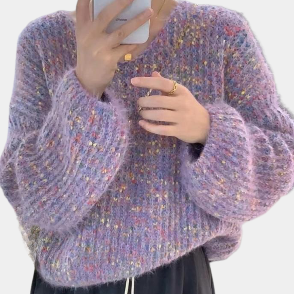 Paarse gebreide trui met kleurrijke stippen, oversized pasvorm, gedragen door persoon die smartphone vasthoudt. Trendy herfstmode, comfortabele kleding.