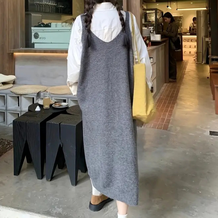 Vrouw in grijze jurk met gele tas in hippe koffiebar, moderne inrichting, houten meubels, casual mode, stedelijke lifestyle.