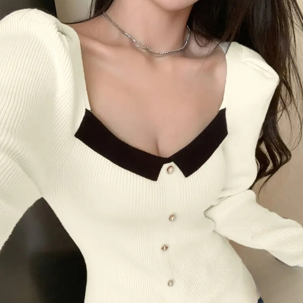 Vrouw draagt stijlvolle crèmekleurige ribgebreide top met zwarte kraag en knoopsluiting, trendy damesmode, elegante kledingstijl.