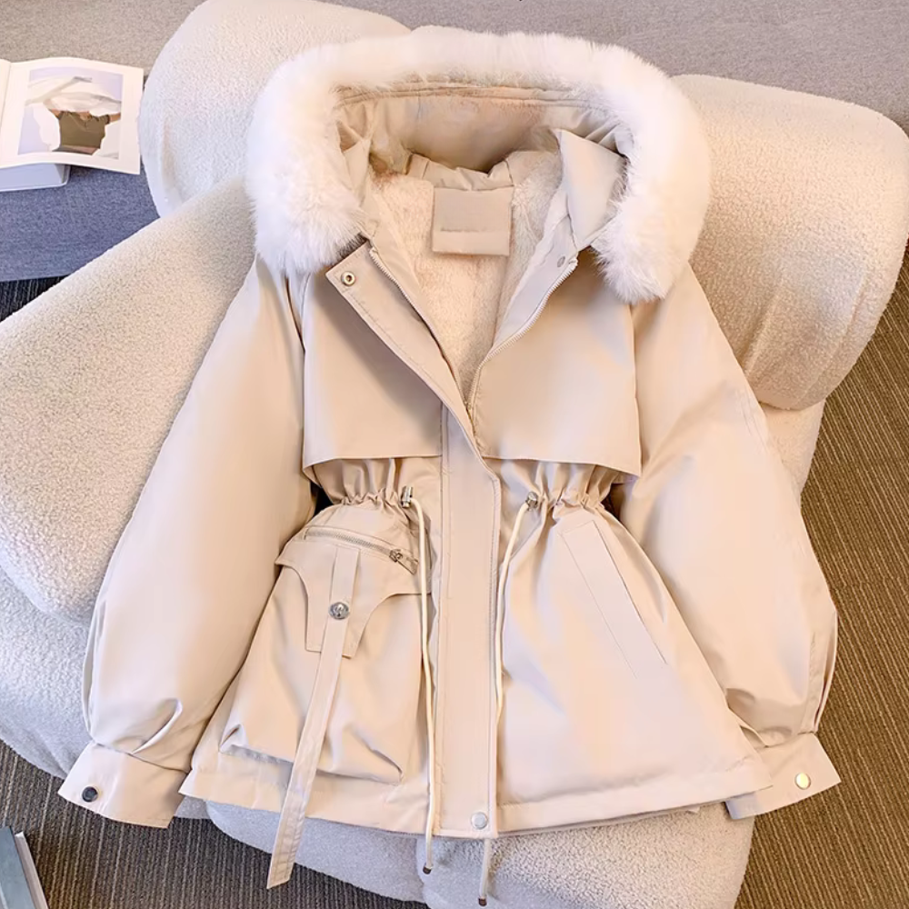 Beige winterjas met capuchon en witte bontkraag, liggend op een stoel. Modieuze damesjas, warme winterkleding, stijlvol en comfortabel ontwerp.