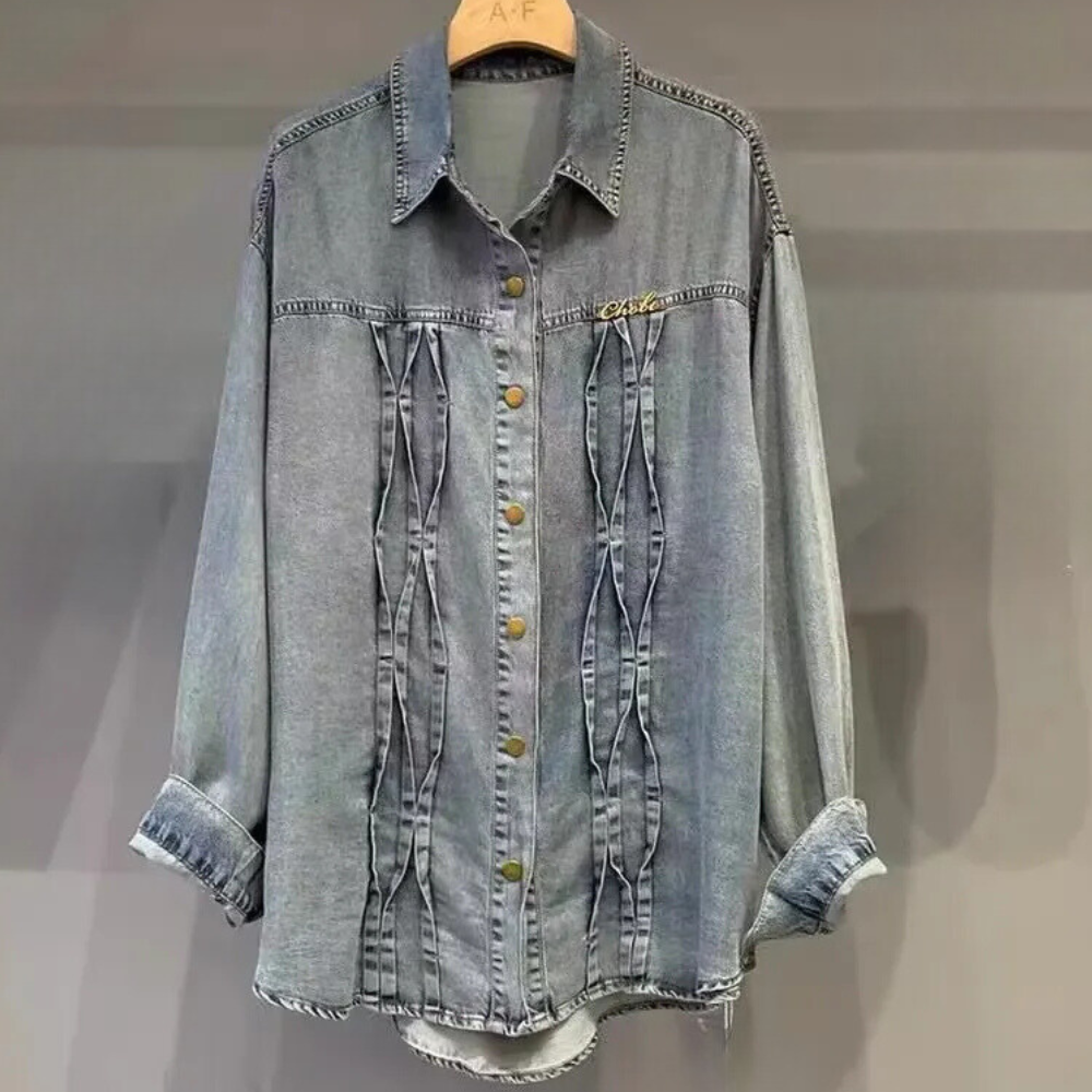 Grijze denim blouse met knoopsluiting, lange mouwen en geplooide details, hangend aan een houten hanger. Modieuze dameskleding, casual stijl.
