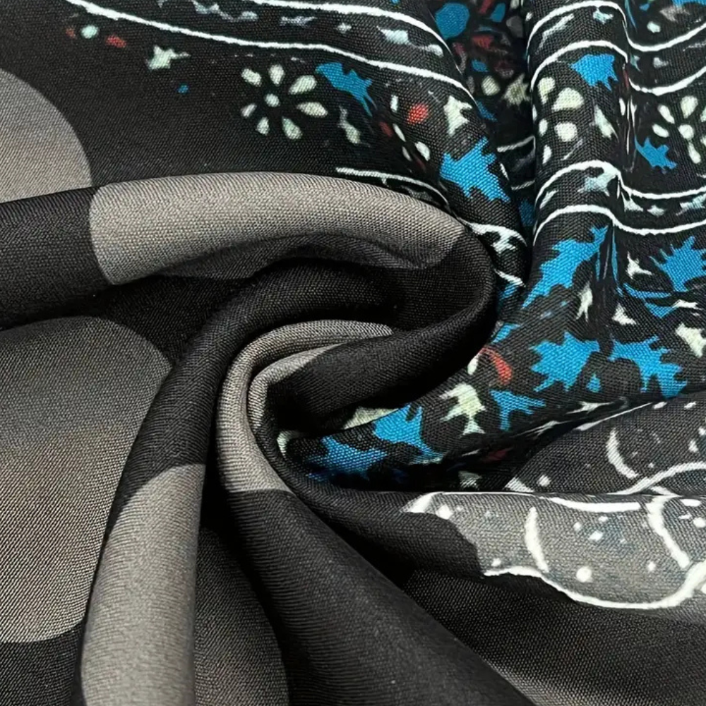 Gevouwen zwarte stof met grijze cirkels en blauwe bloemenprint, close-up textuur, hoogwaardige textielmaterialen, modieuze stoffenontwerpen.