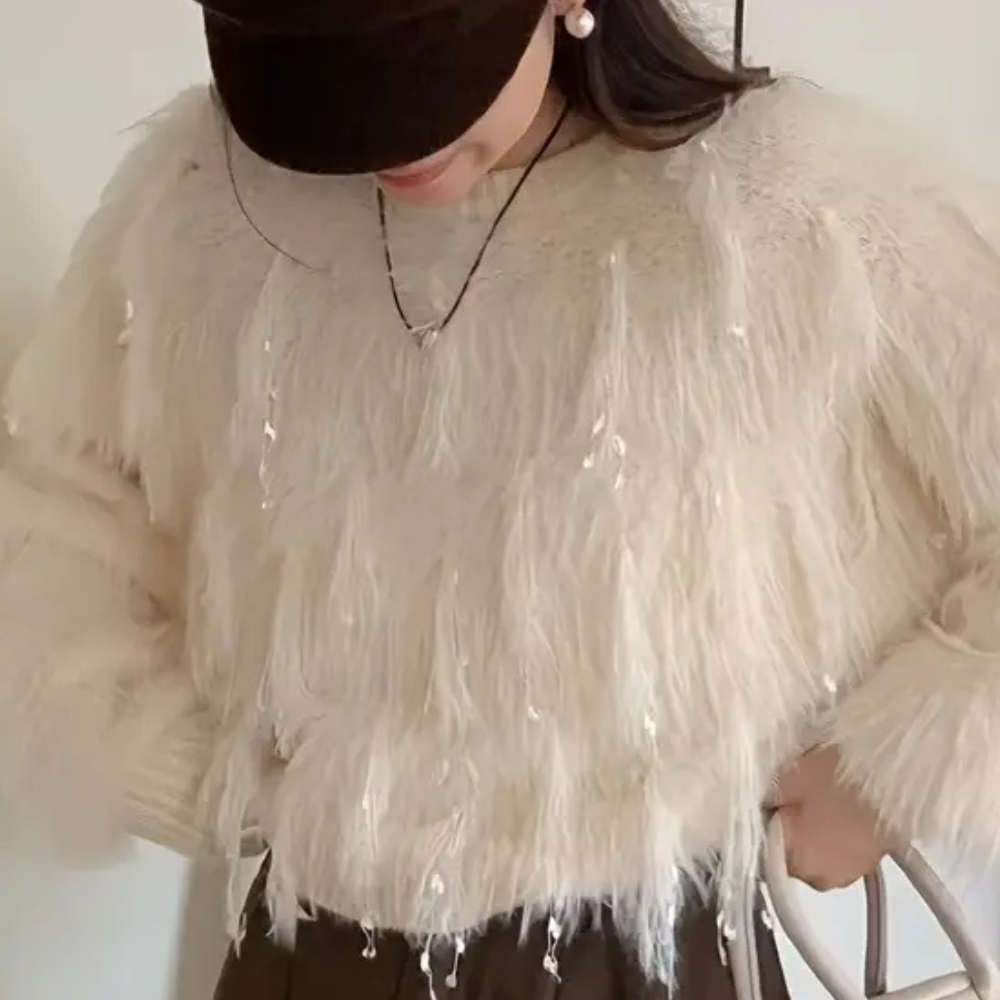 Vrouw in witte pluizige trui met pailletten, bruine broek en zwarte pet. Modieuze winterkleding, trendy damesmode, casual outfit.