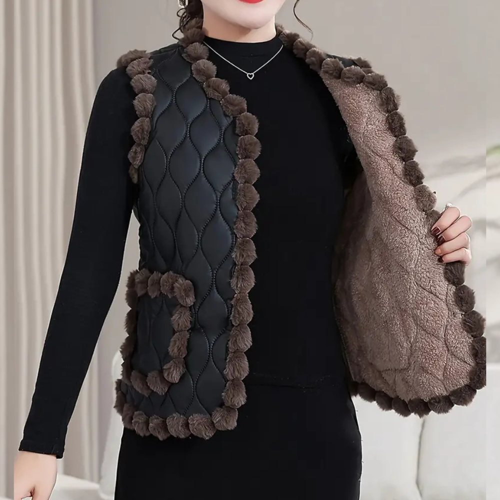 Vrouw draagt zwarte gewatteerde bodywarmer met bruine bontdetails en zakken, perfect voor herfstmode. Stijlvolle dameskleding, warme winteroutfit.