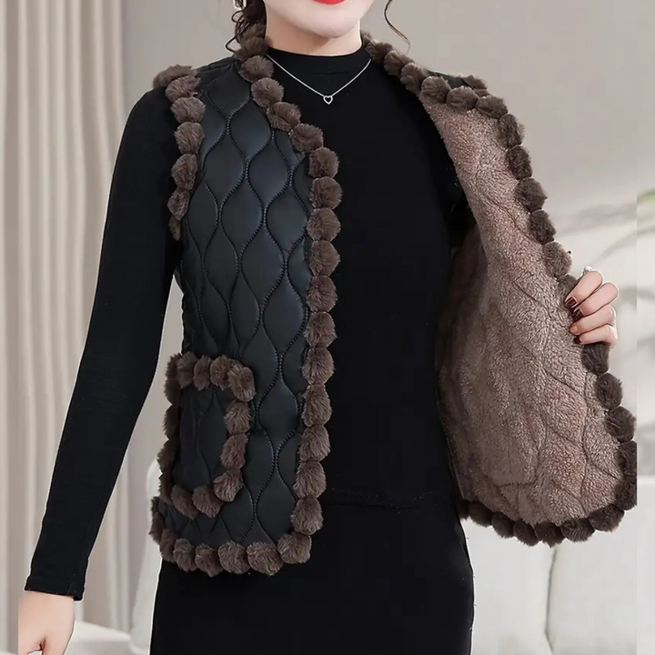 Vrouw draagt zwarte gewatteerde bodywarmer met bruine bontdetails en zakken, perfect voor herfstmode. Stijlvolle dameskleding, warme winteroutfit.