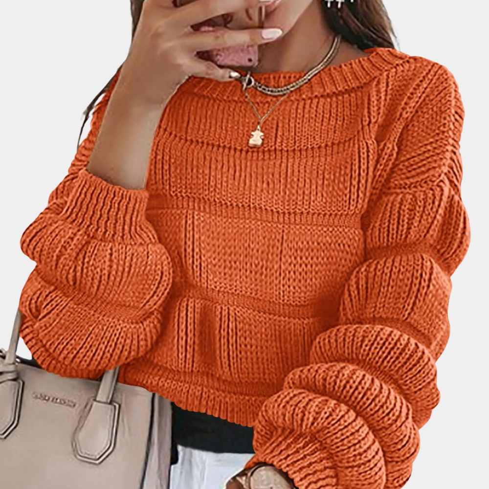 Vrouw in oranje gebreide trui met pofmouwen, houdt een beige handtas vast. Modieuze herfstkleding, trendy damesmode, casual stijl.