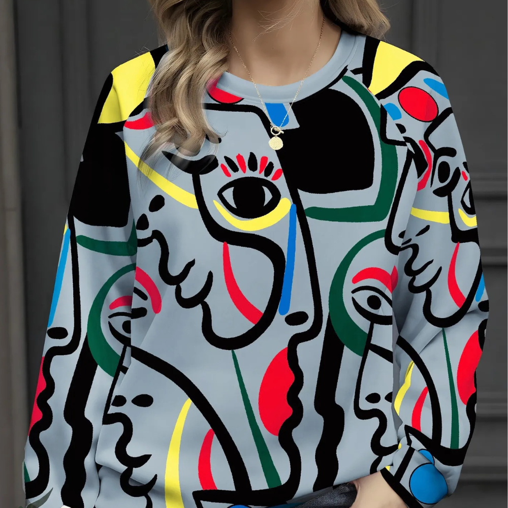 Vrouw draagt kleurrijke abstracte trui met gezichten en geometrische patronen, perfect voor modieuze streetwear en kunstliefhebbers.