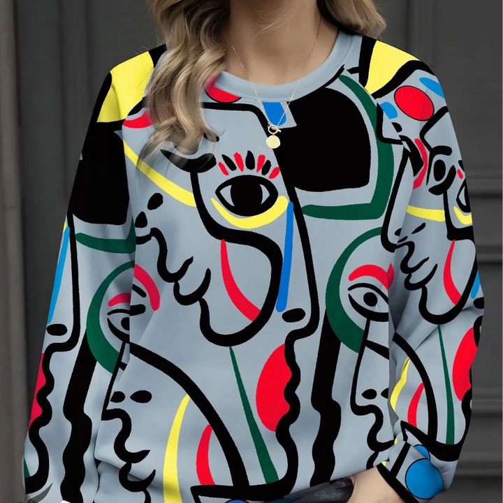 Vrouw draagt kleurrijke abstracte trui met gezichten en geometrische patronen, perfect voor modieuze streetwear en kunstliefhebbers.