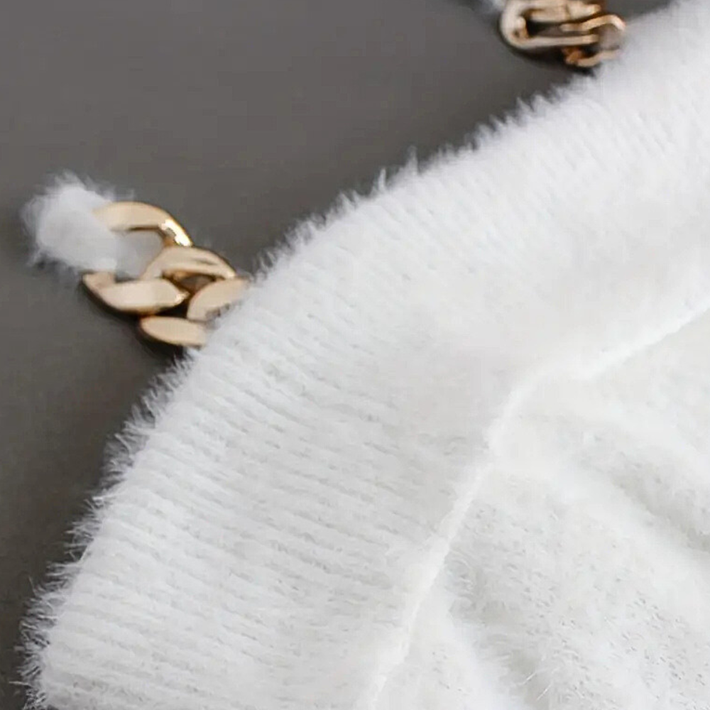 Witte gebreide trui met gouden kettingdetails, zachte textuur, close-up. Modieuze dameskleding, herfst-winter trend, luxe uitstraling.