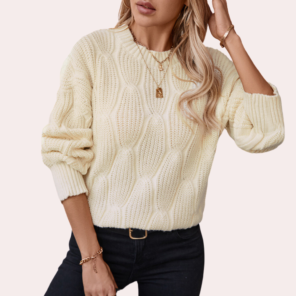 Vrouw in crèmekleurige kabeltrui met gouden sieraden, casual mode, herfstkleding, trendy damesoutfit, stijlvolle trui, modieuze look.