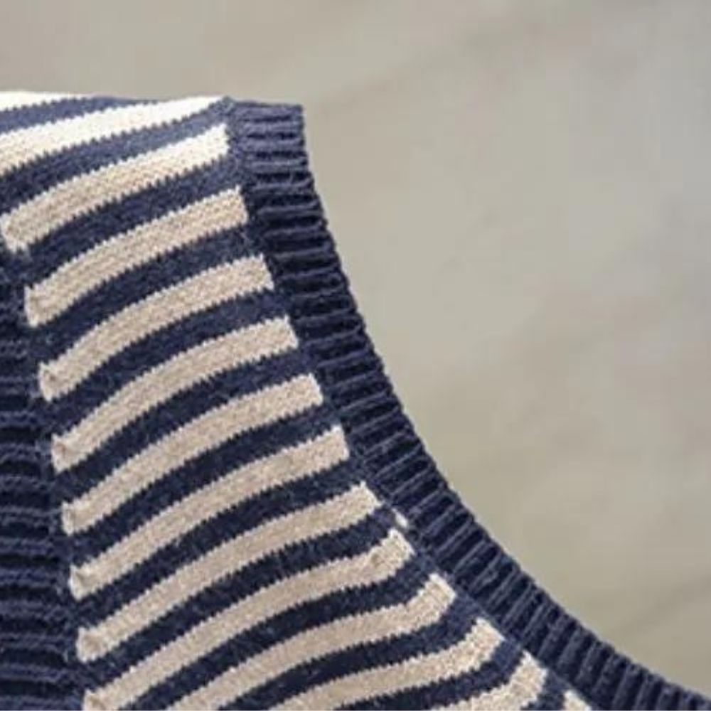 Donkerblauw-wit gestreepte trui, close-up van de stoftextuur. Modieuze gebreide kleding, comfortabele wintermode, hoogwaardige materialen.