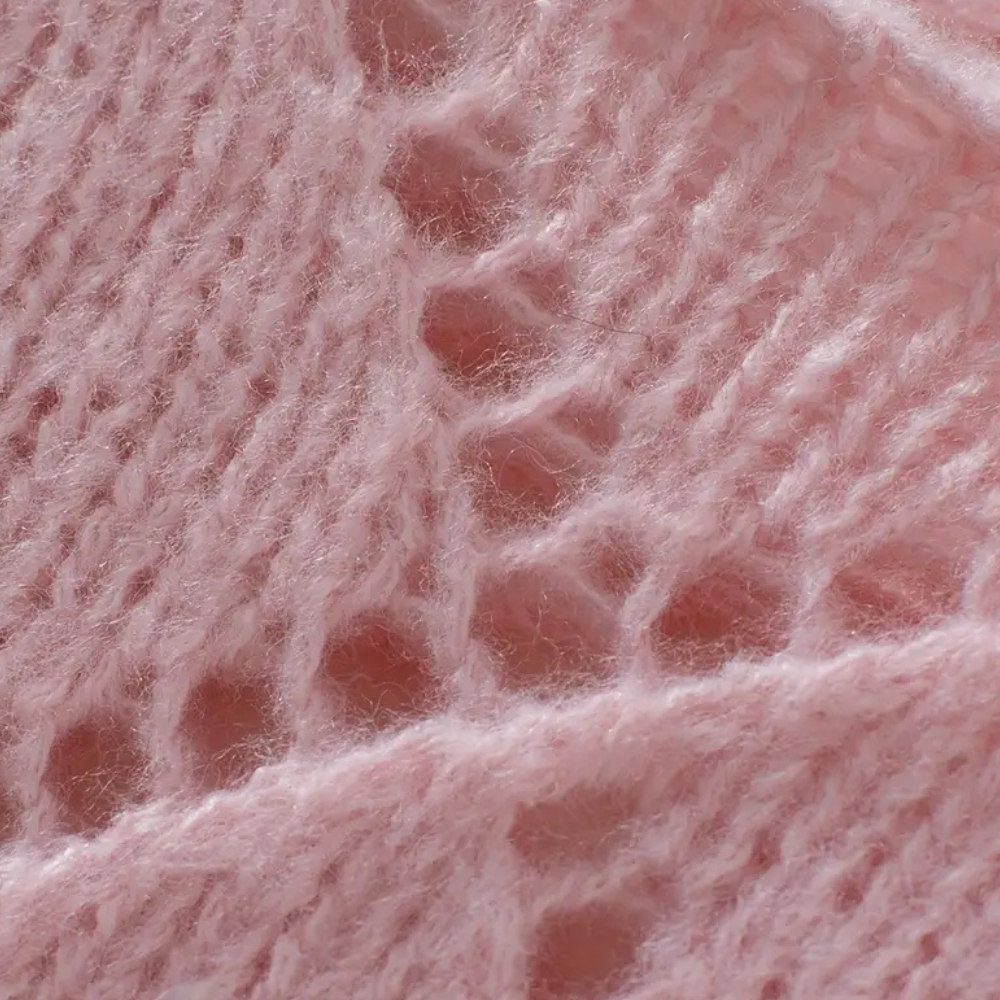 Roze gebreide stof close-up, zachte textuur, opengewerkt patroon, wol, breiwerk, handgemaakt, modetrend, comfortabele kleding.