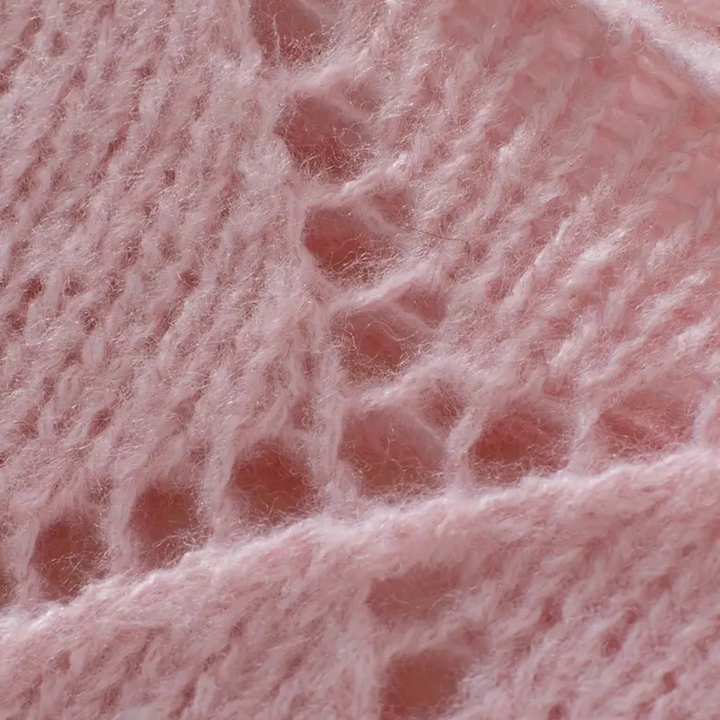 Roze gebreide stof close-up, zachte textuur, opengewerkt patroon, wol, breiwerk, handgemaakt, modetrend, comfortabele kleding.