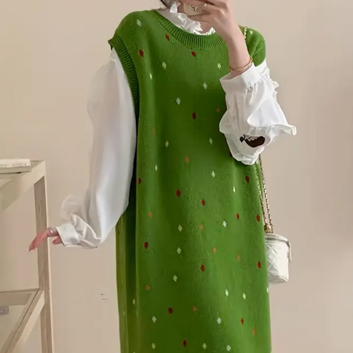 Groene gebreide jurk met kleurrijke stippen, gedragen over een witte blouse met ruches. Trendy damesmode, herfstoutfit, casual chique stijl.