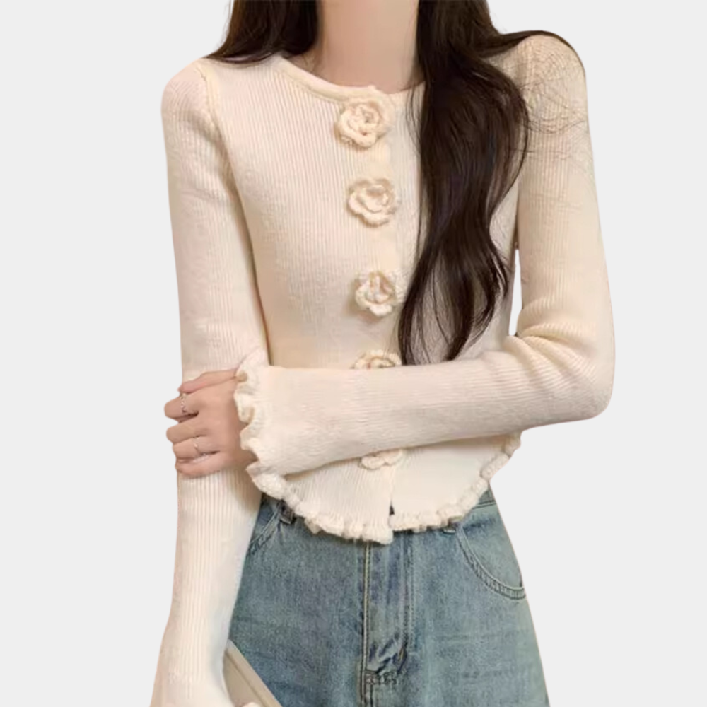Witte gebreide damestrui met bloemenknopen, lange mouwen en geribbelde randen, gecombineerd met blauwe jeans. Modieuze casual outfit.