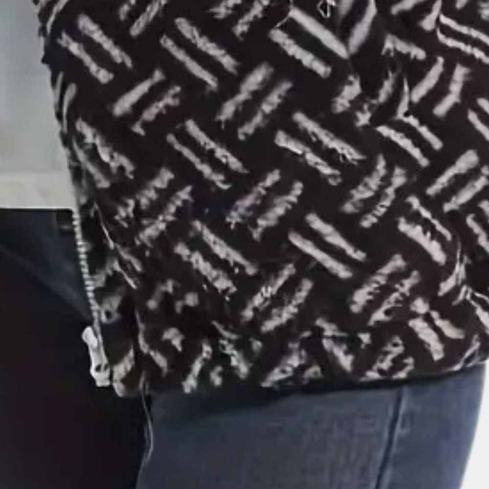 Zwart-witte gebreide trui met geometrisch patroon, gedragen door persoon in blauwe jeans. Modieuze winterkleding, warme textuur.