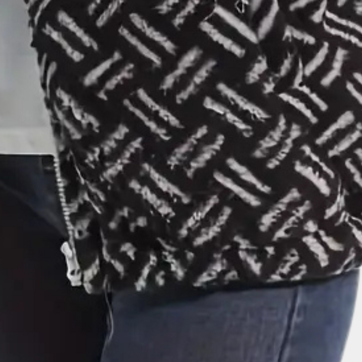 Zwart-witte gebreide trui met geometrisch patroon, gedragen door persoon in blauwe jeans. Modieuze winterkleding, warme textuur.