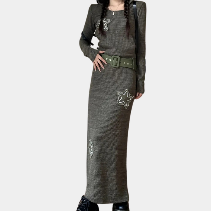 Grijze gebreide maxi-jurk met lange mouwen, sterapplicaties en brede groene riem. Trendy damesmode, herfstkleding, casual chique stijl.