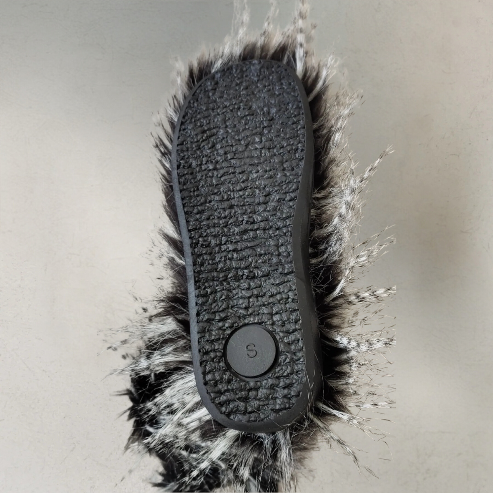Zwarte rubberen zool van een harige pantoffel, maat S, met grijs-witte vachttextuur. Comfortabele, warme pantoffel voor thuisgebruik.