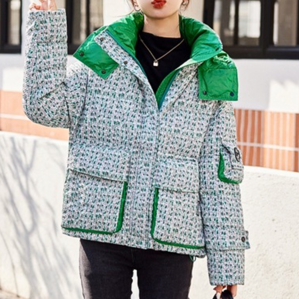 Vrouw draagt stijlvolle, gewatteerde winterjas met groene accenten en patroon, ideaal voor koude seizoenen. Trendy damesmode, warme kleding.