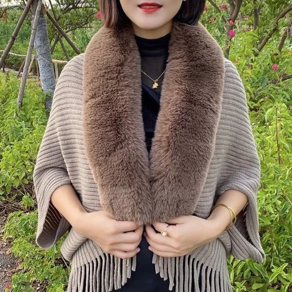 Vrouw met bruine bontsjaal en beige poncho met franjes, buiten in groene omgeving. Stijlvolle herfstmode, warme accessoires, trendy dameskleding.