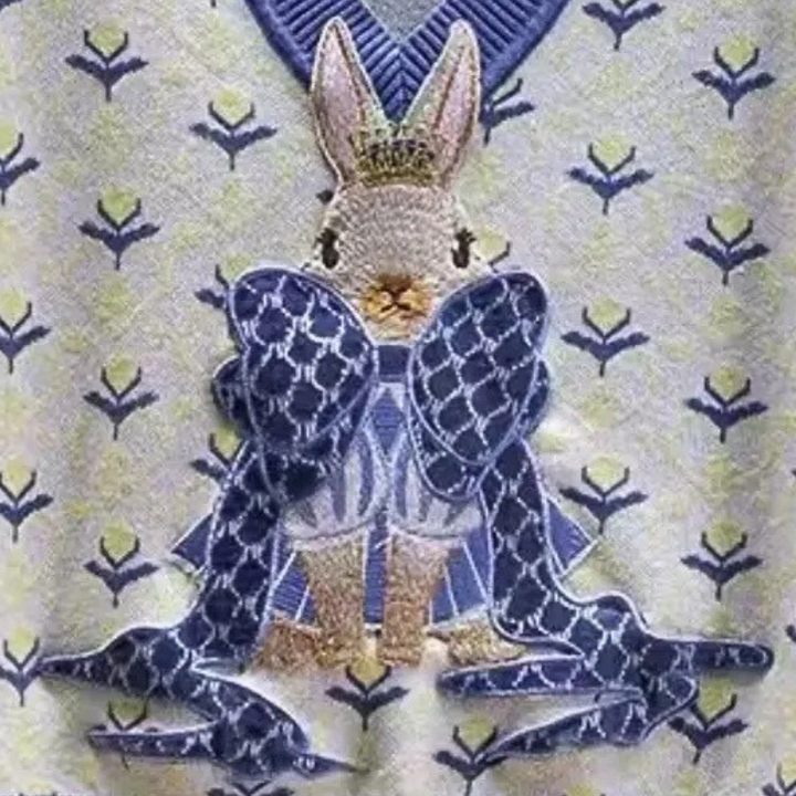 Konijn met kroon en blauwe strik op geborduurde stof met bloemenpatroon, luxe design, decoratieve textielkunst, koninklijk thema.