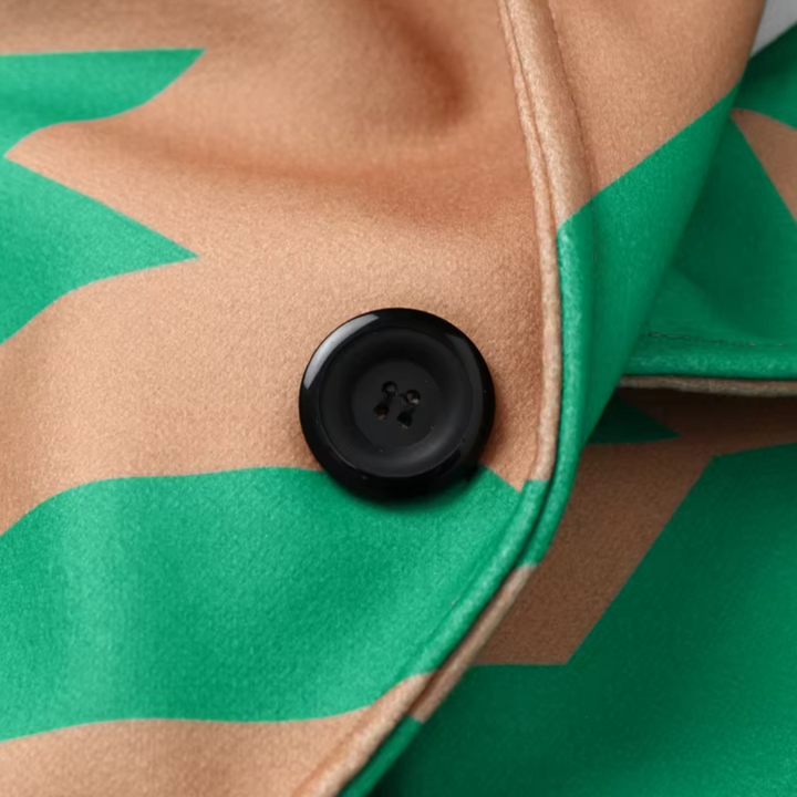 Beige en groene jas met zigzagpatroon en zwarte knoop, close-up. Modieuze dameskleding, trendy herfstjas, stijlvolle knoopdetails.
