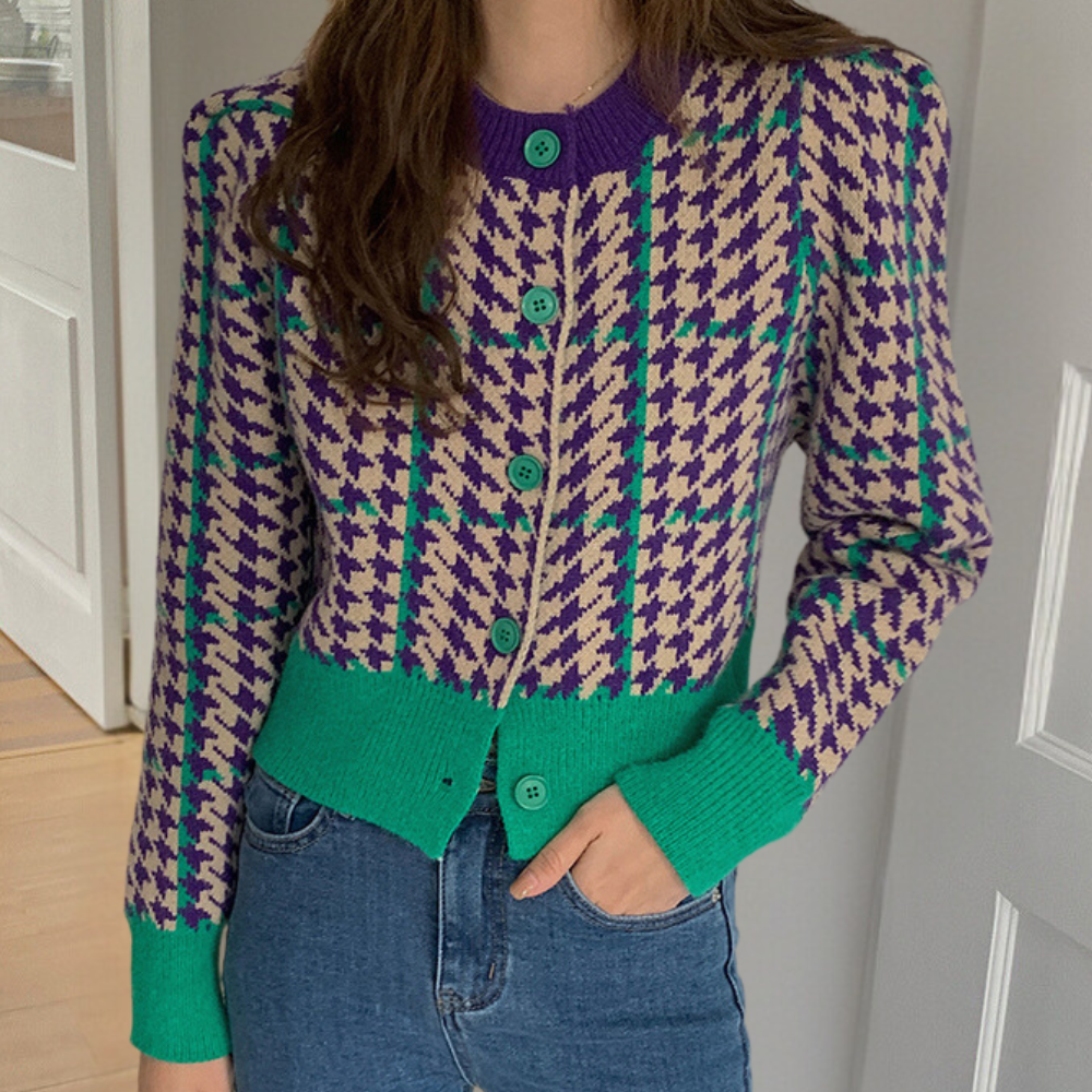 Vrouw draagt kleurrijk pied-de-poule vest met paarse en groene accenten, gecombineerd met blauwe jeans. Modieuze dameskleding, herfststijl.