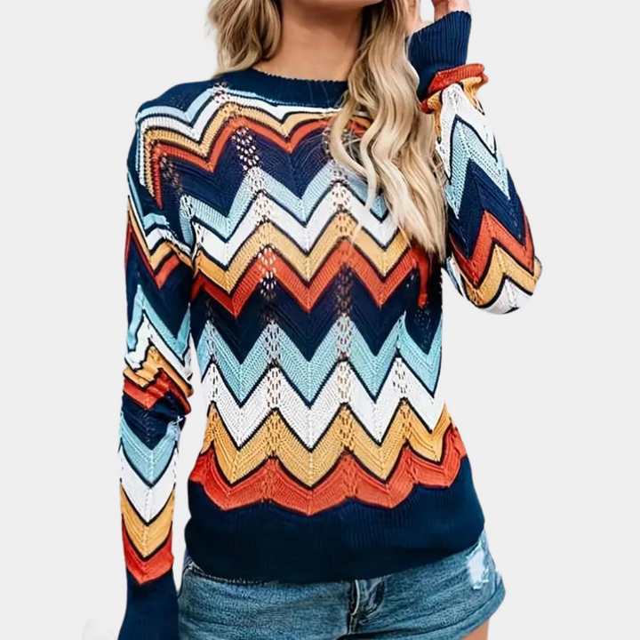 Vrouw draagt kleurrijke zigzag trui met lange mouwen en denim shorts. Modieuze dameskleding, herfstoutfit, casual stijl.