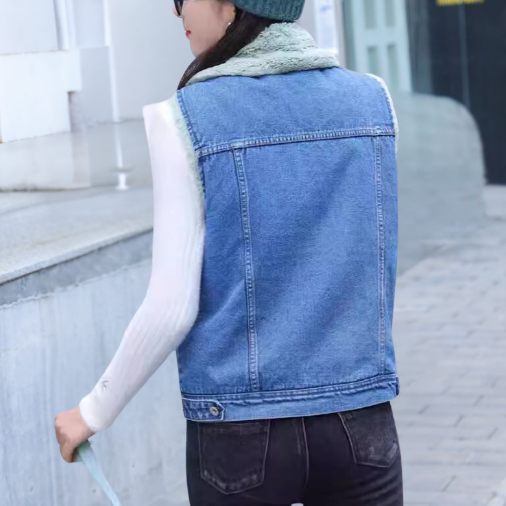 Vrouw in blauwe spijkerjas en zwarte jeans loopt buiten. Casual wintermode, trendy denim outfit, stedelijke achtergrond.