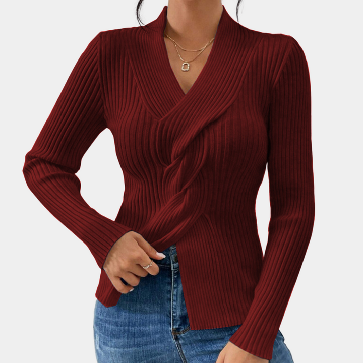 Vrouw draagt bordeauxrode geribbelde trui met V-hals en lange mouwen, gecombineerd met blauwe jeans. Modieuze dameskleding, herfststijl.