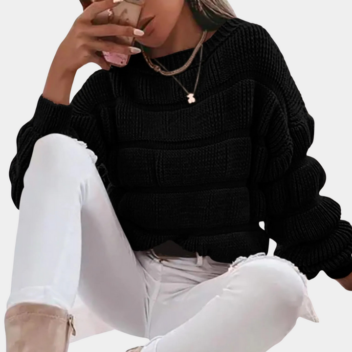 Vrouw in zwarte gebreide trui en witte jeans, drinkt koffie. Modieuze herfstoutfit, casual stijl, comfortabele kleding.