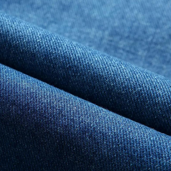 Blauwe denim stof close-up, textuur van hoogwaardige jeansstof, ideaal voor modeontwerp en kledingproductie.