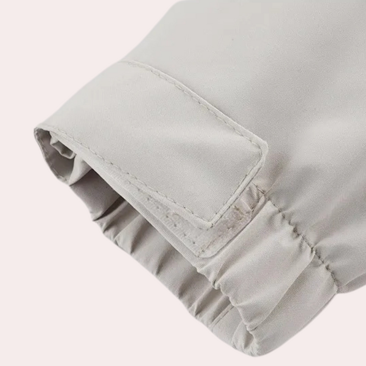 Lichtgrijze jas met elastische manchetten, detailopname. Hoogwaardige stof, modieuze kleding, comfortabele pasvorm, trendy design.